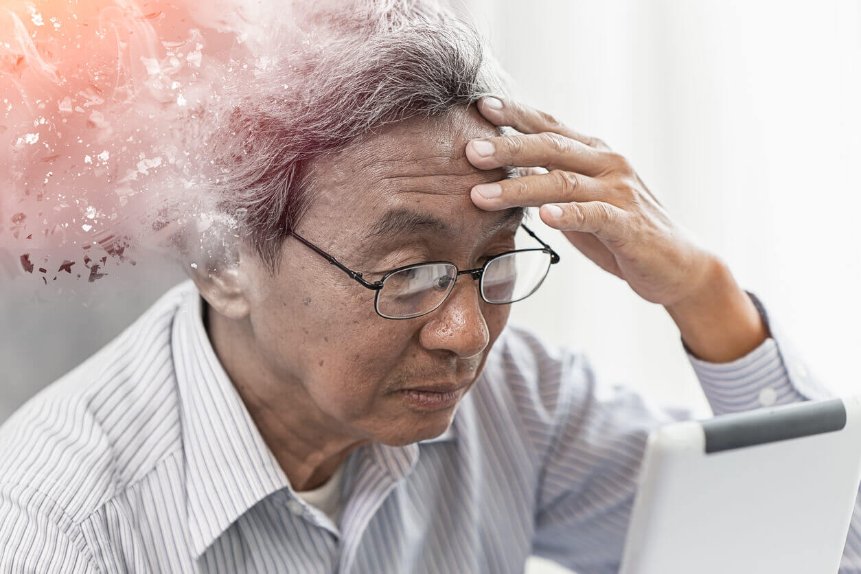 Older adult holding his forehead while looking at a tablet, illustrating the stress that memory loss and cognitive worry can cause